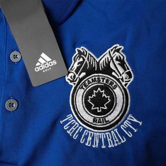 Vêtements personnalisés de qualité pour événements, équipes ou objets promotionnels. Logo du client brodé en noir et blanc, sur un polo adidas bleu vif.